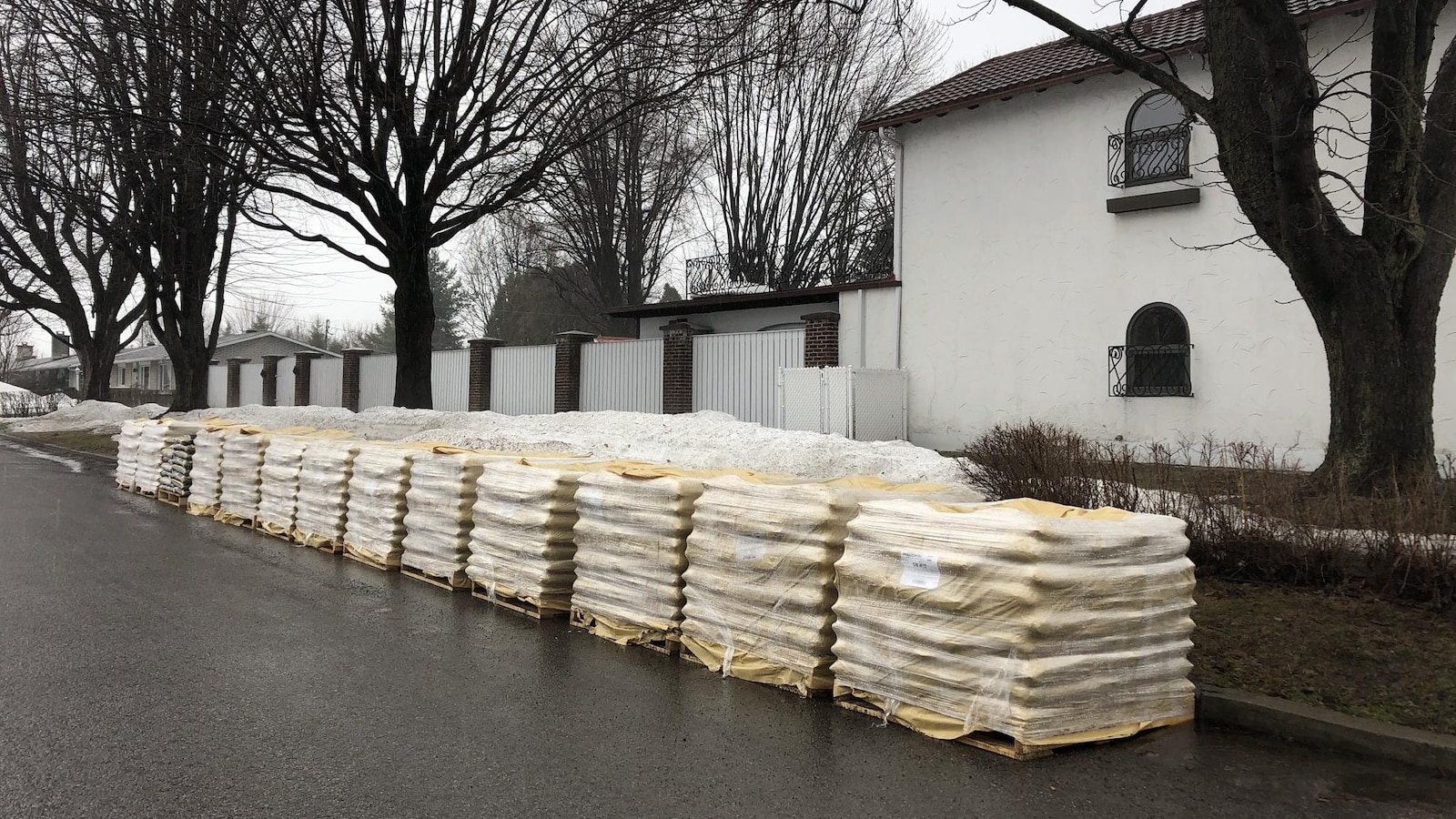Des sacs de sable, sur des palettes de bois, déposées sans être utilisés sur une rue fantôme.