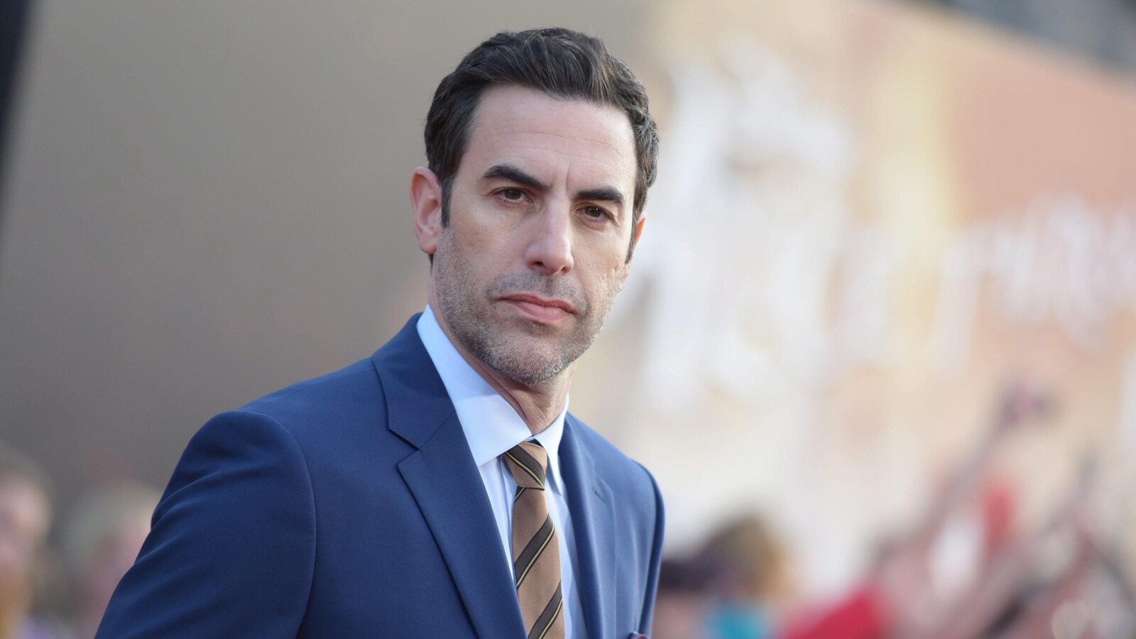 Portrait de Sacha Baron Cohen vêtu d'une veste bleue.