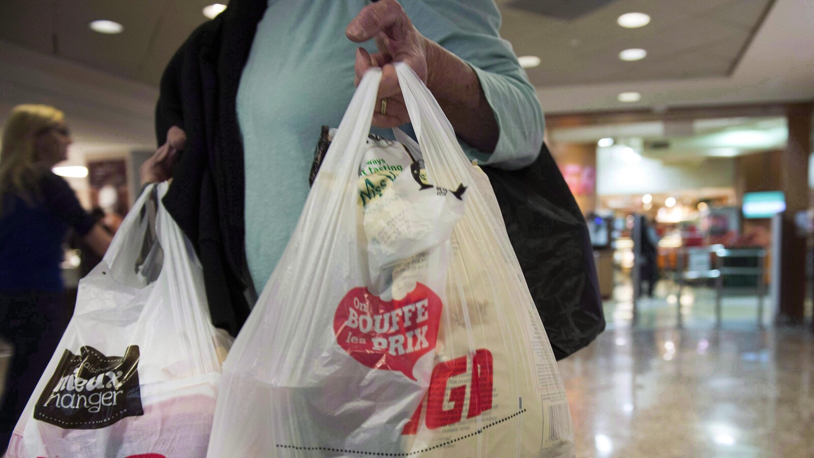 Une femme tient des sacs de plastique à la main.