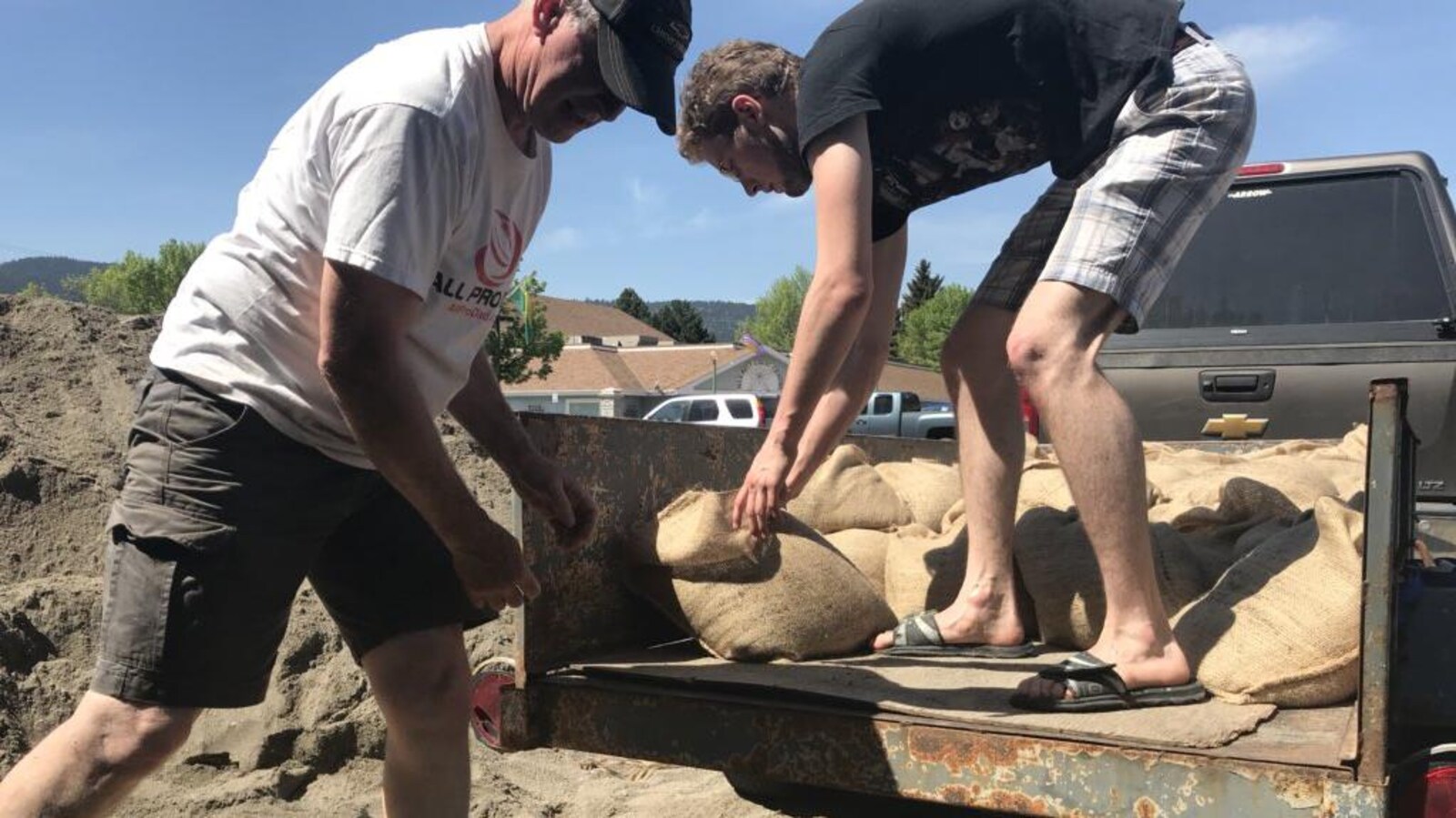 Deux hommes transportent des sacs de sable.