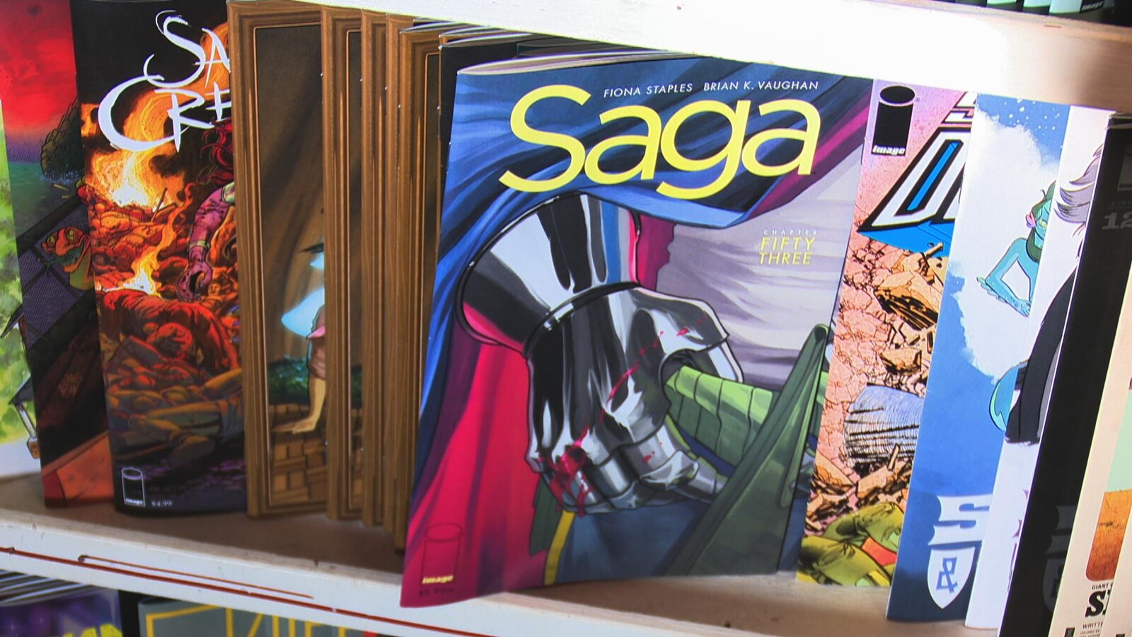 Une étagère avec des bandes dessinées, dont Saga au premier plan.