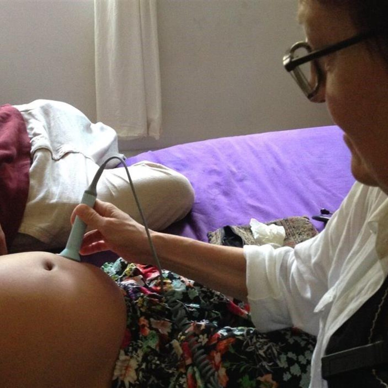 Une sage-femme ausculte un cœur fœtal à l’aide d’un appareil à ultrasons.