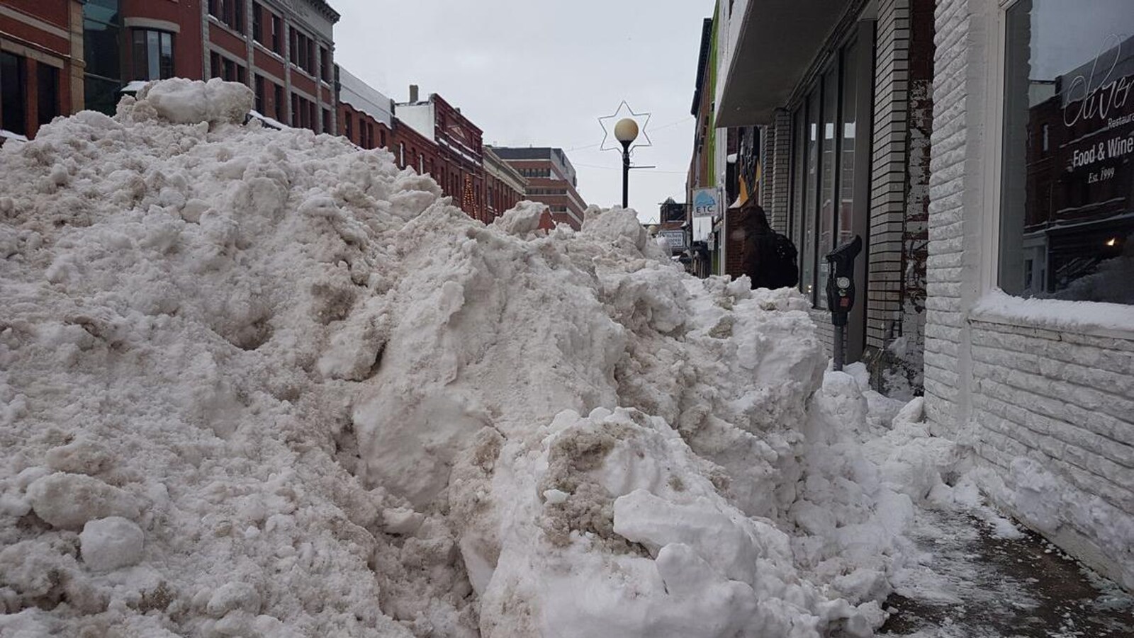 Un énorme monticule de neige bloque le trottoir devant le restaurant