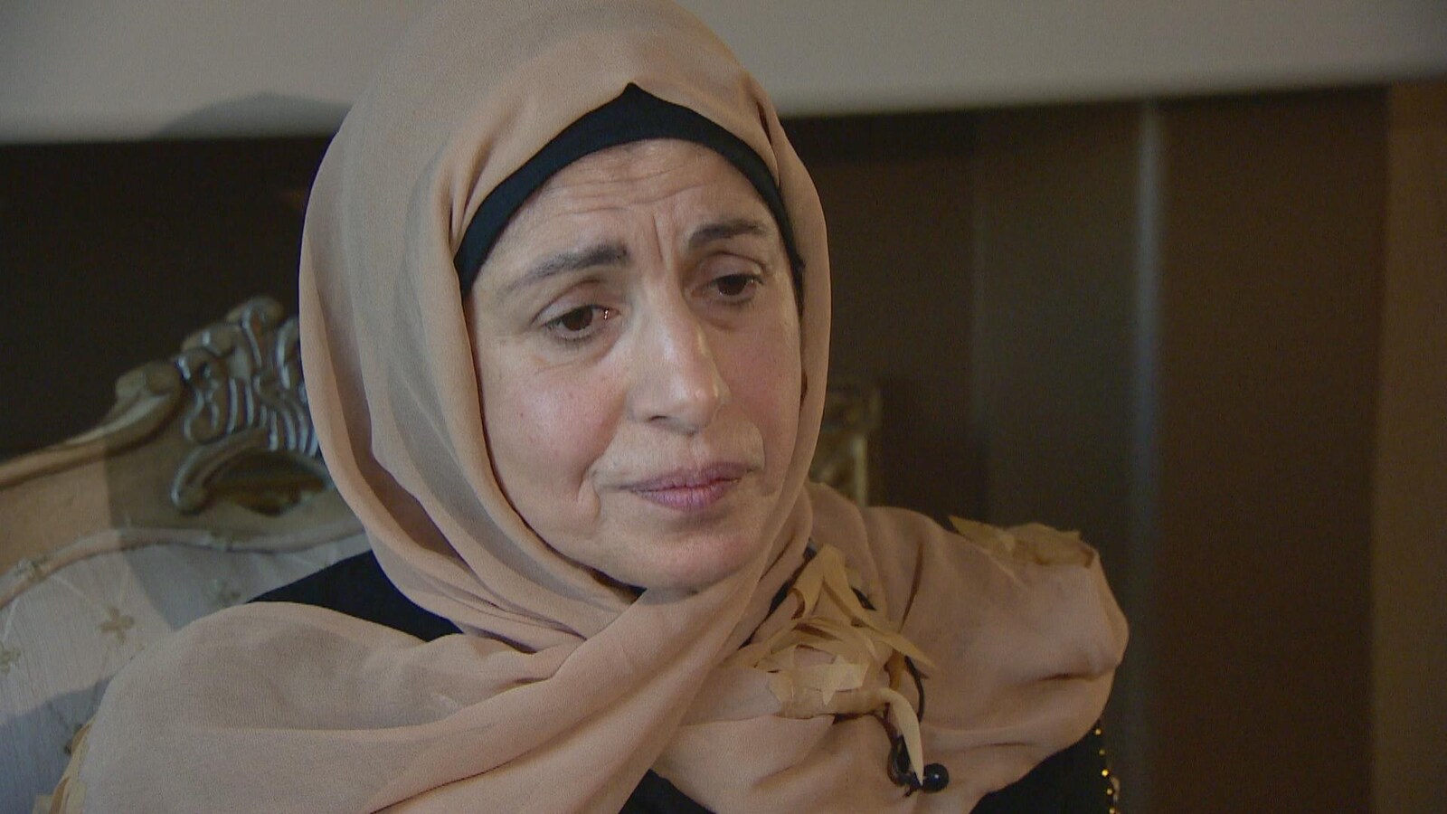 Salwa Atwi porte un hidjab brun. Elle a les yeux baissés et une expression triste.