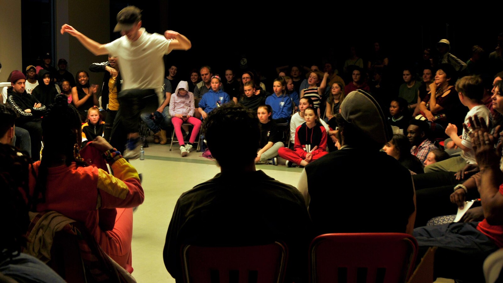 Un adolescent danse sous le regard attentif du public rassemblé autour de la piste.