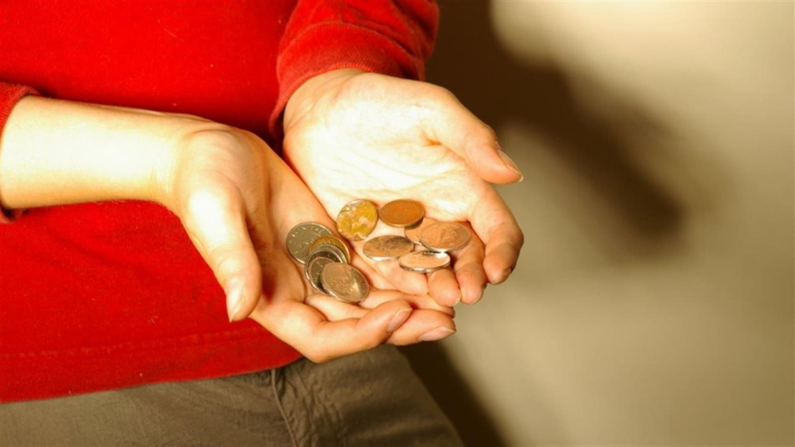 Une personne tient quelques cents dans ses mains