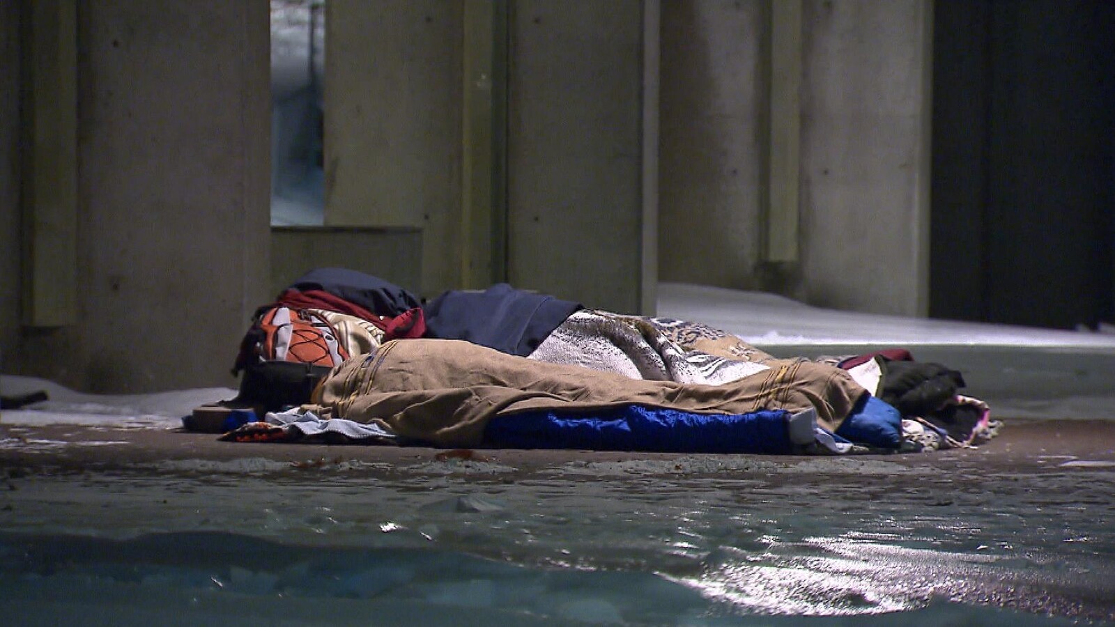 Une personne itinérante dormant dans la rue, dans des couvertures, en hiver.