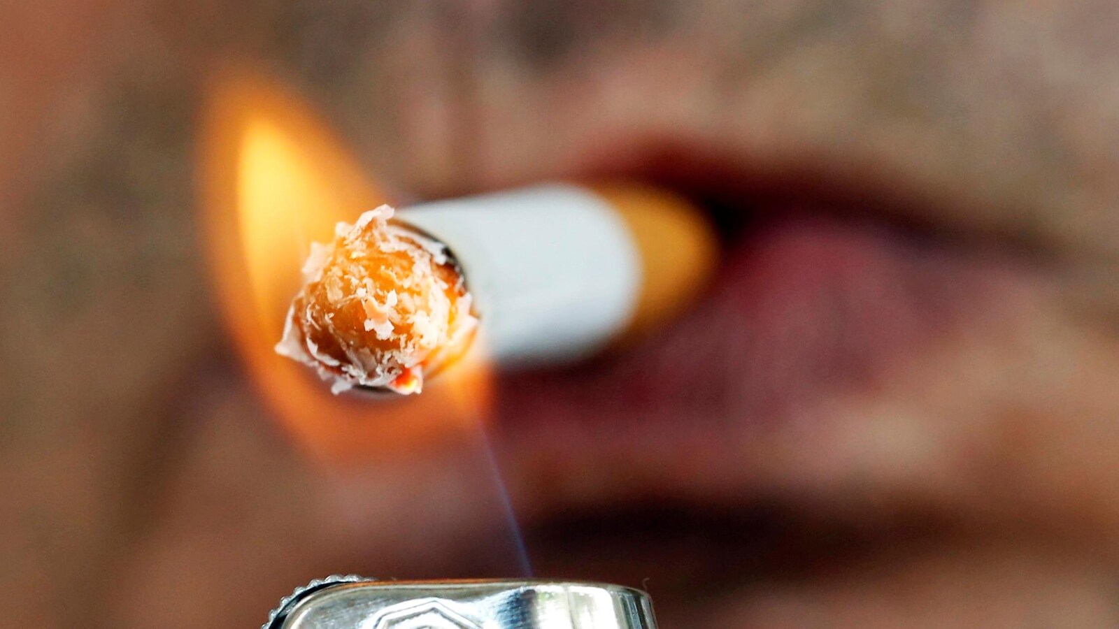 Un homme s'allume une cigarette avec un briquet.