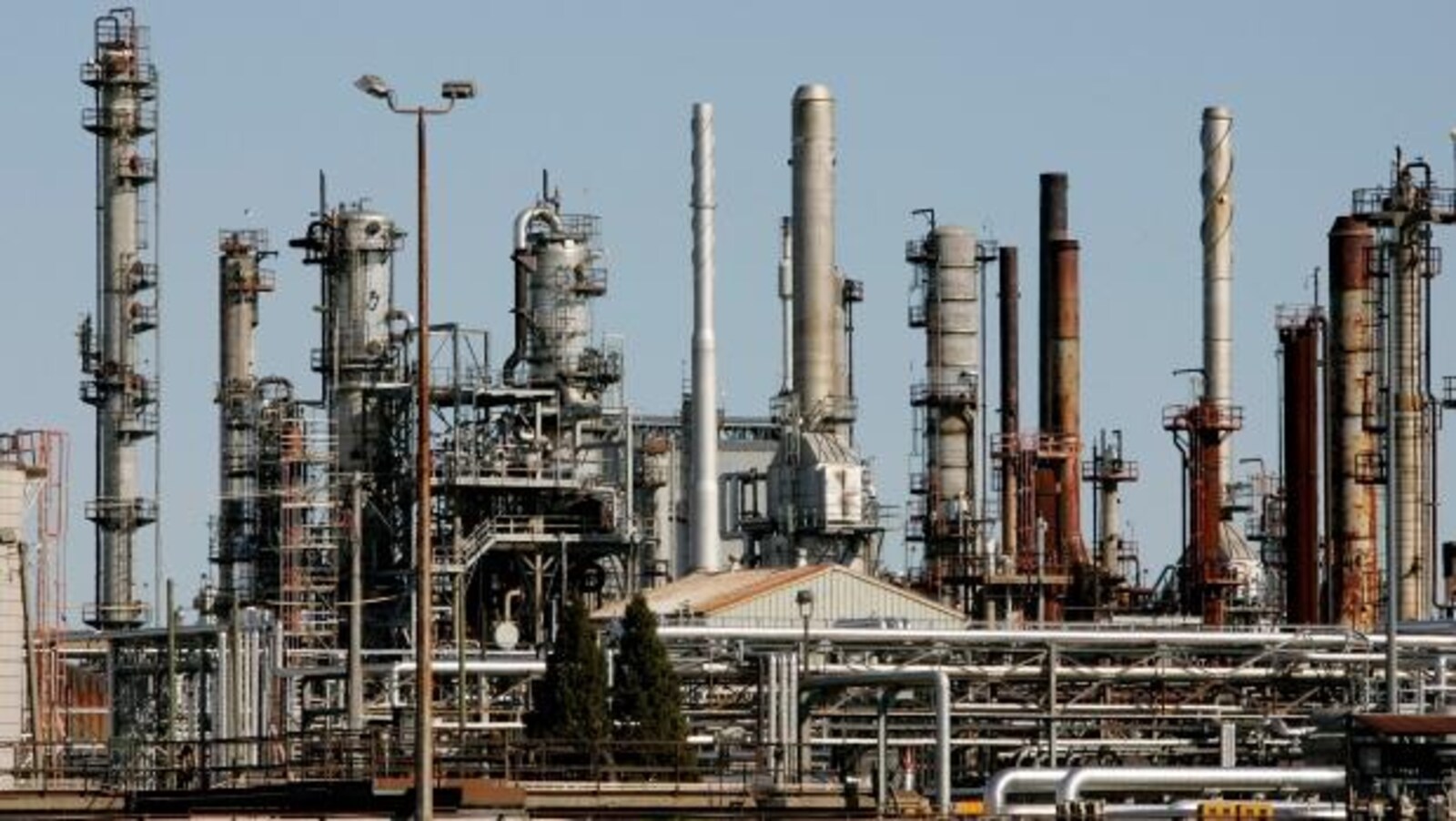 Gros plan d'une dizaine de cheminées d'une raffinerie de prétrole.