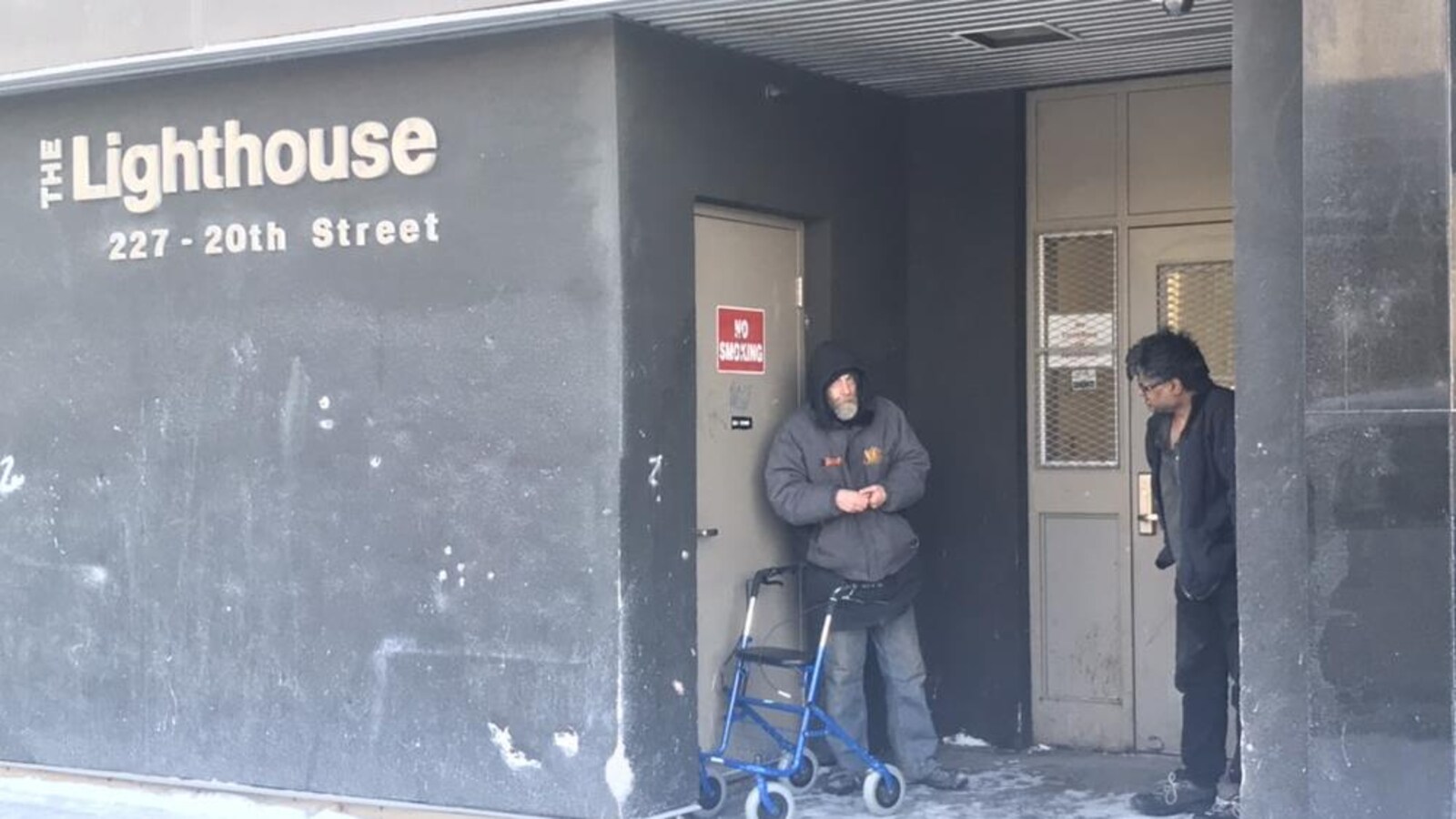 Deux hommes attendent à l'extérieur de l'immeuble du Lighthouse de Saskatoon.