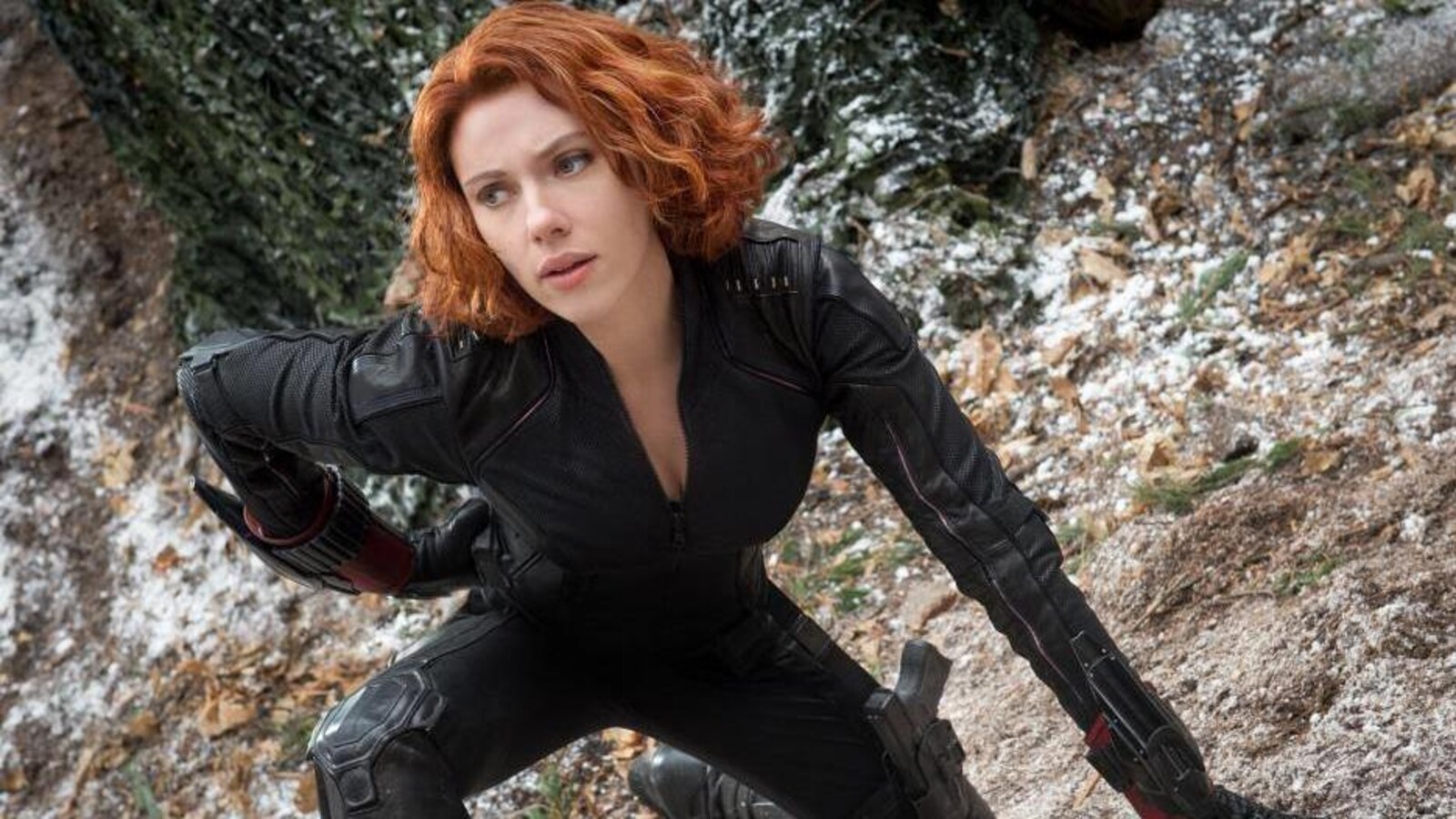 Scarlett Johansson dans le rôle de la Veuve noire est accroupie, un genou à terre, sur un sol rocailleux, dans le film <i>Avengers : L'ère d'Ultron</i> (2015).