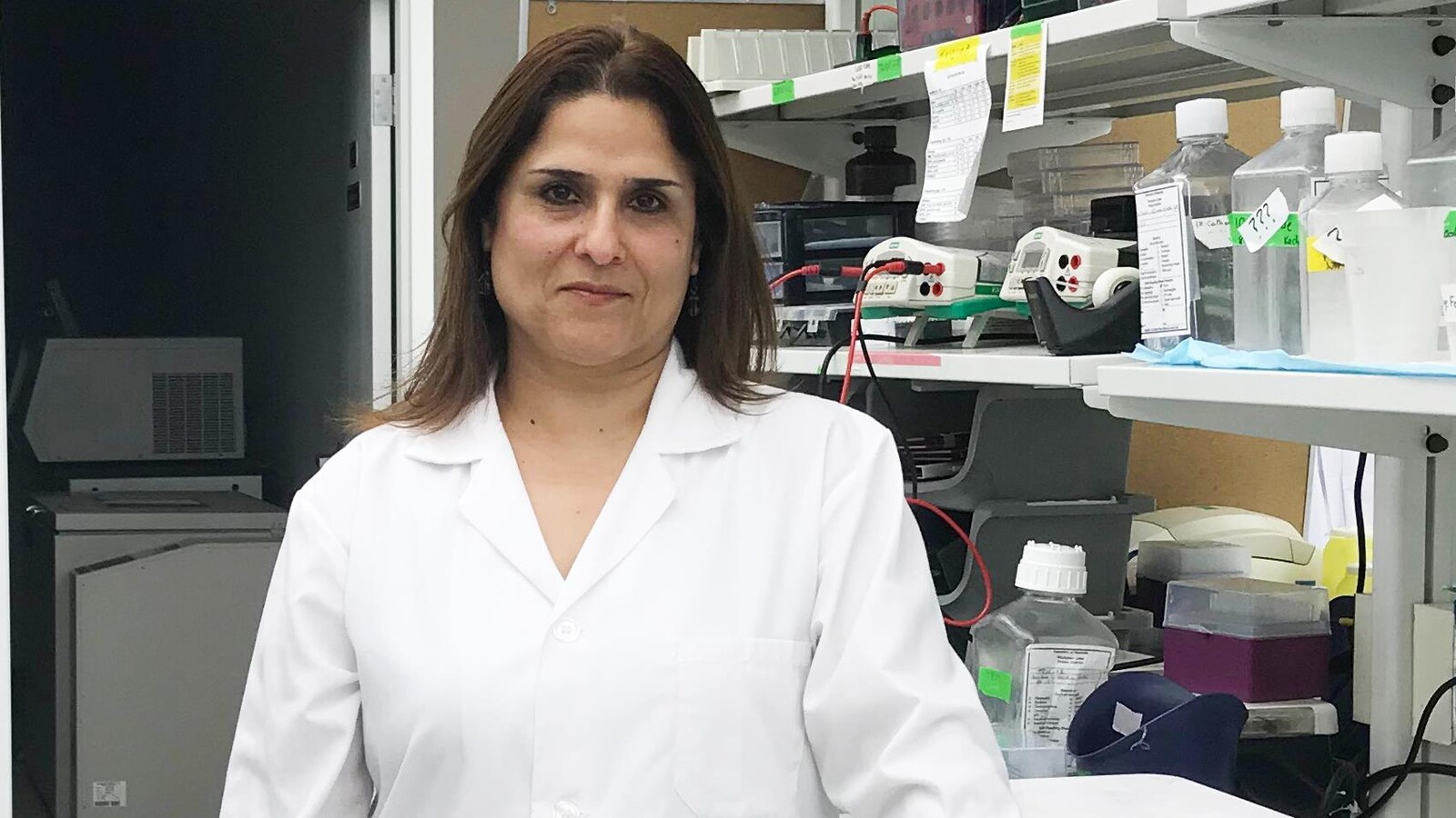 Une chercheuse vêtue d'une blouse blanche dans un laboratoire.