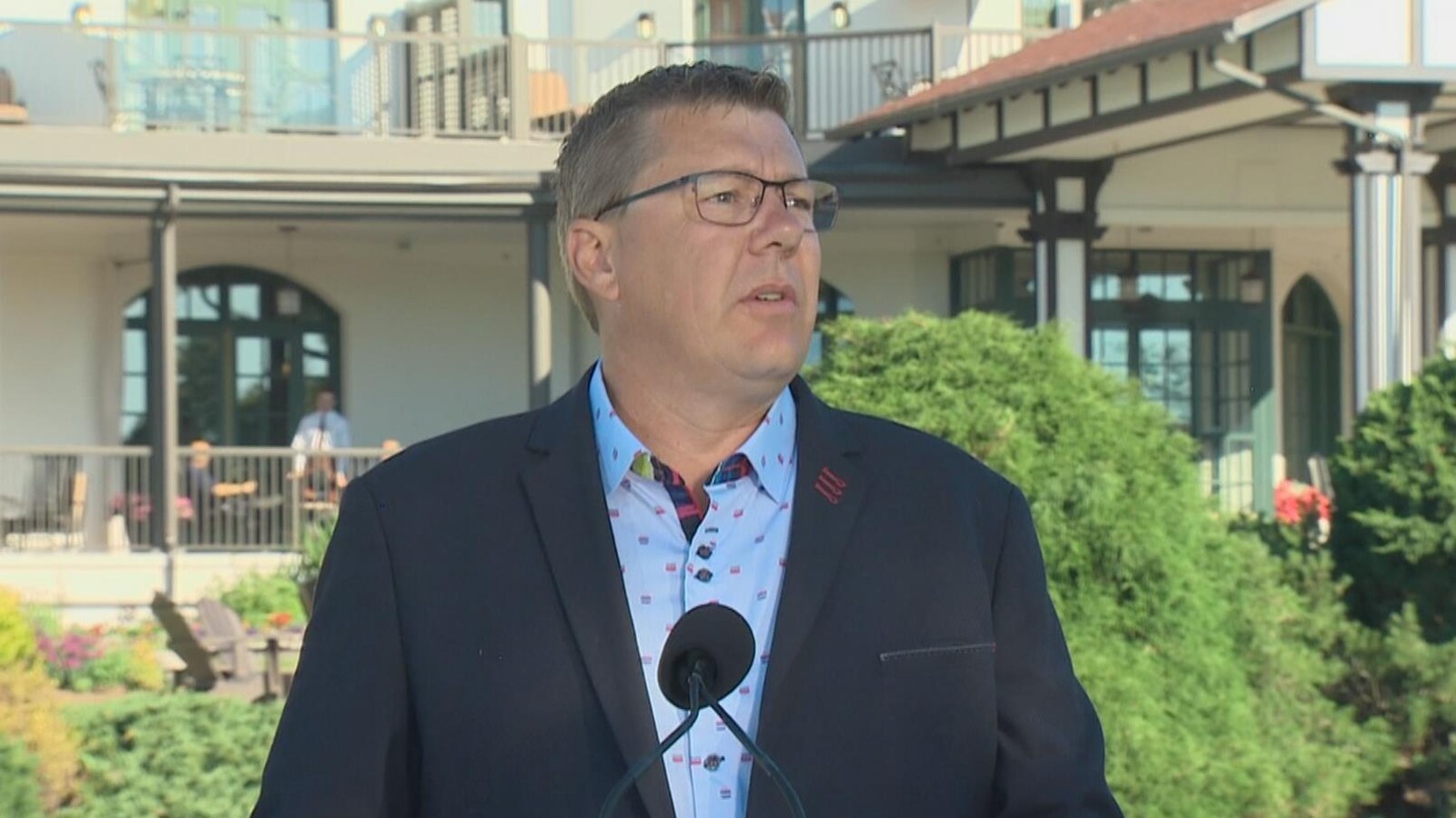 Photo d'un homme en complet devant un micro au podium