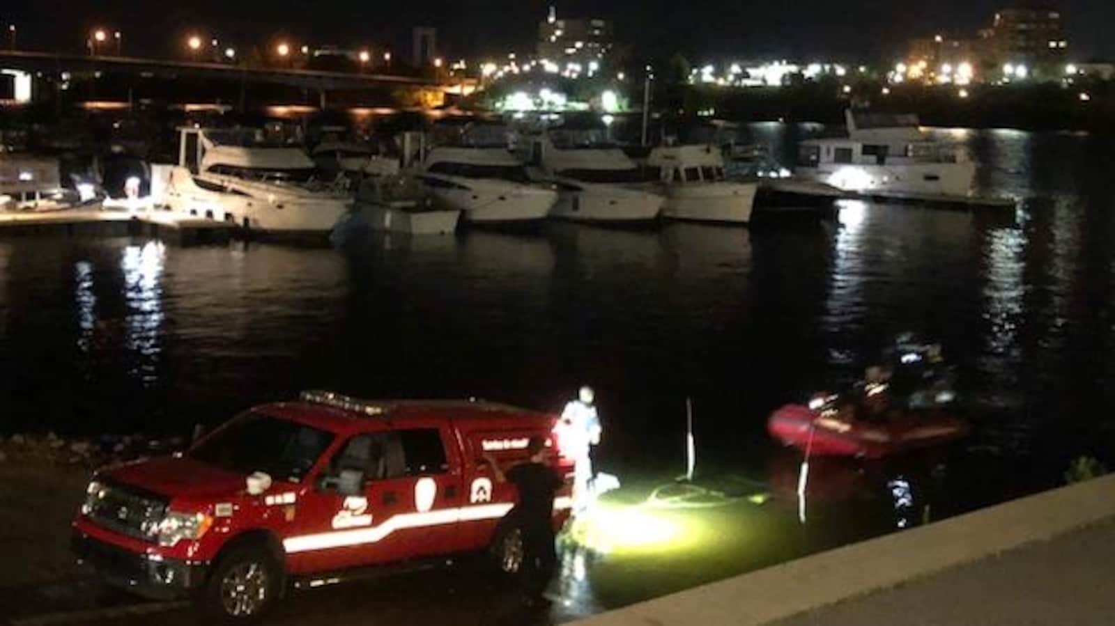 Un bateau pneumatique et une voiture des services d'urgences dans une marina.