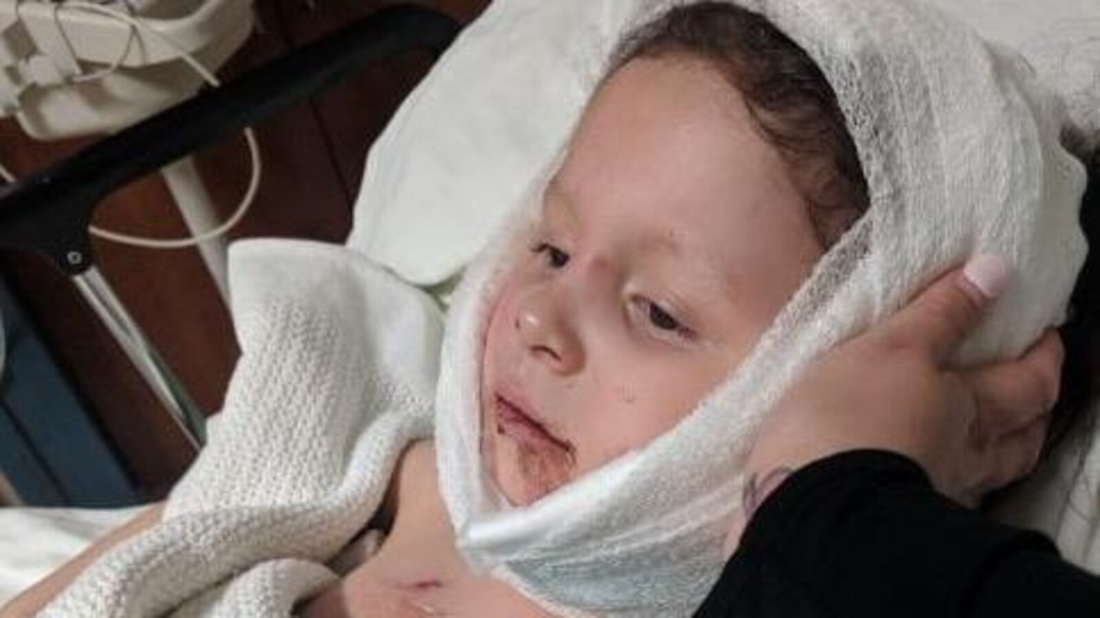Une jeune fille dans un lit d'hôpital, un bandage à la tête.