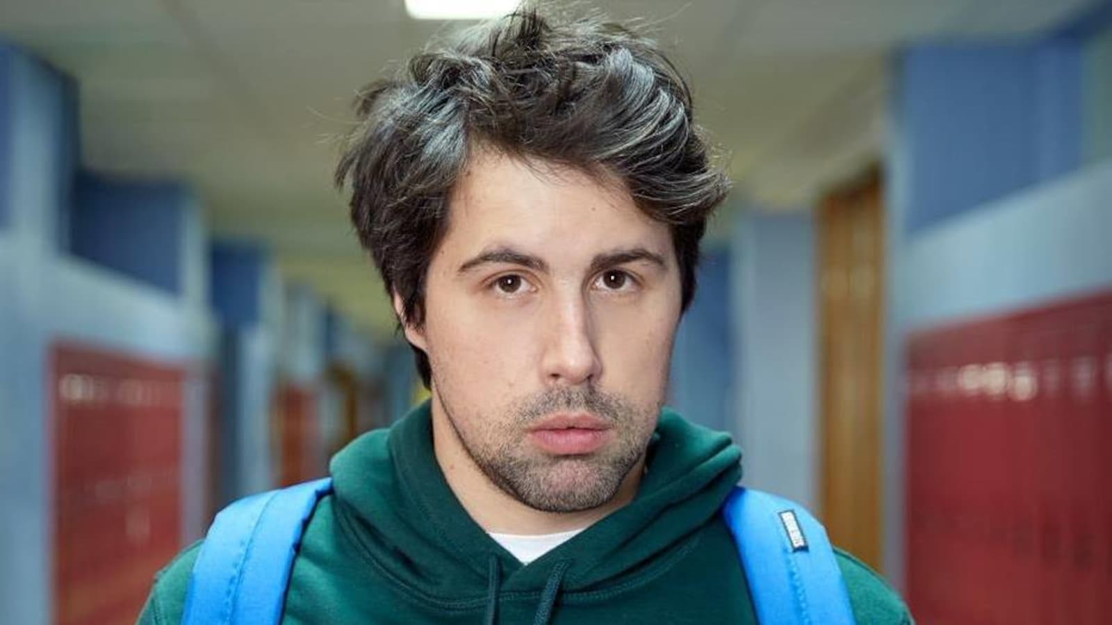 Philippe-Audrey-Larrue-St-Jacques est dans un couloir d'école, et porte un sac à dos.