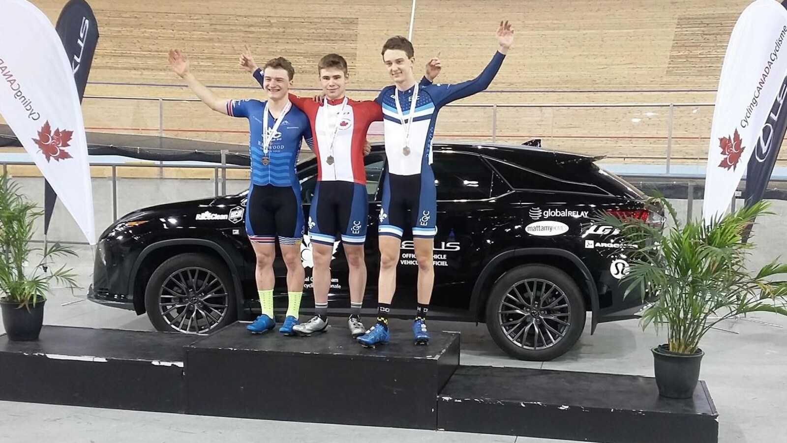 Trois cyclistes sur un podium devant la piste de vélo.