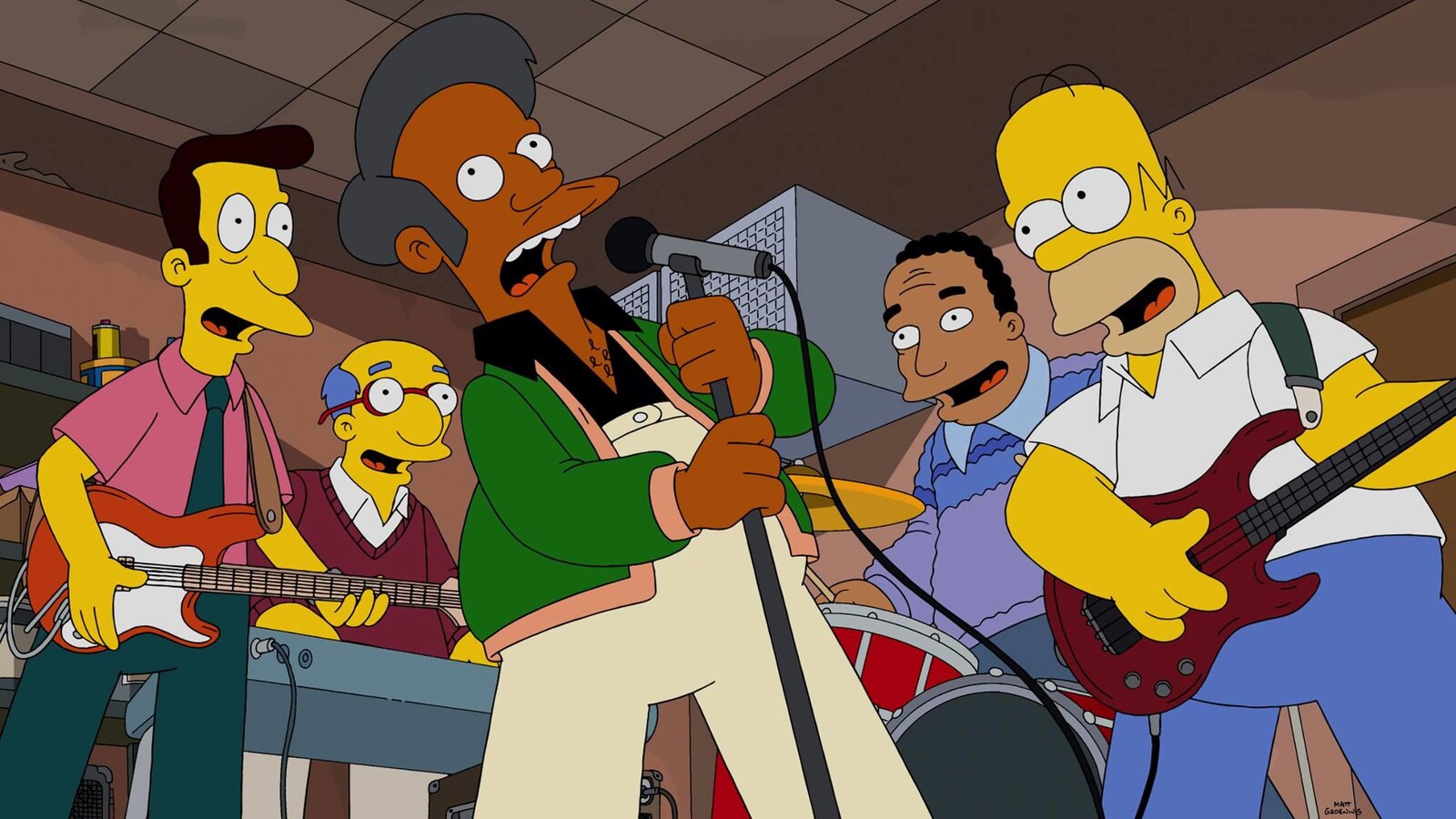 Apu chante au micro entouré d'autres personnages de série Les Simpson.