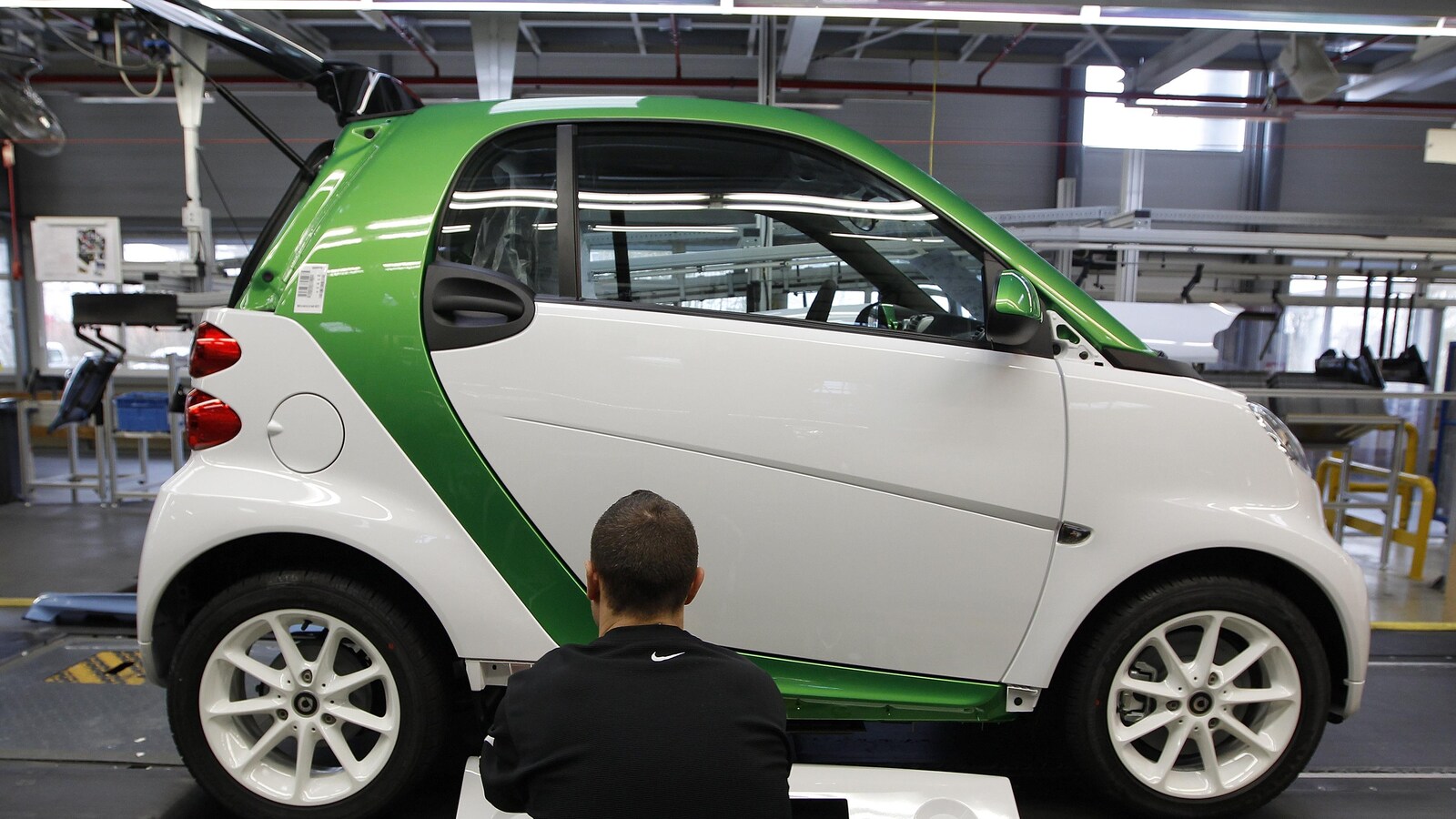 Un homme répare une voiture électrique.