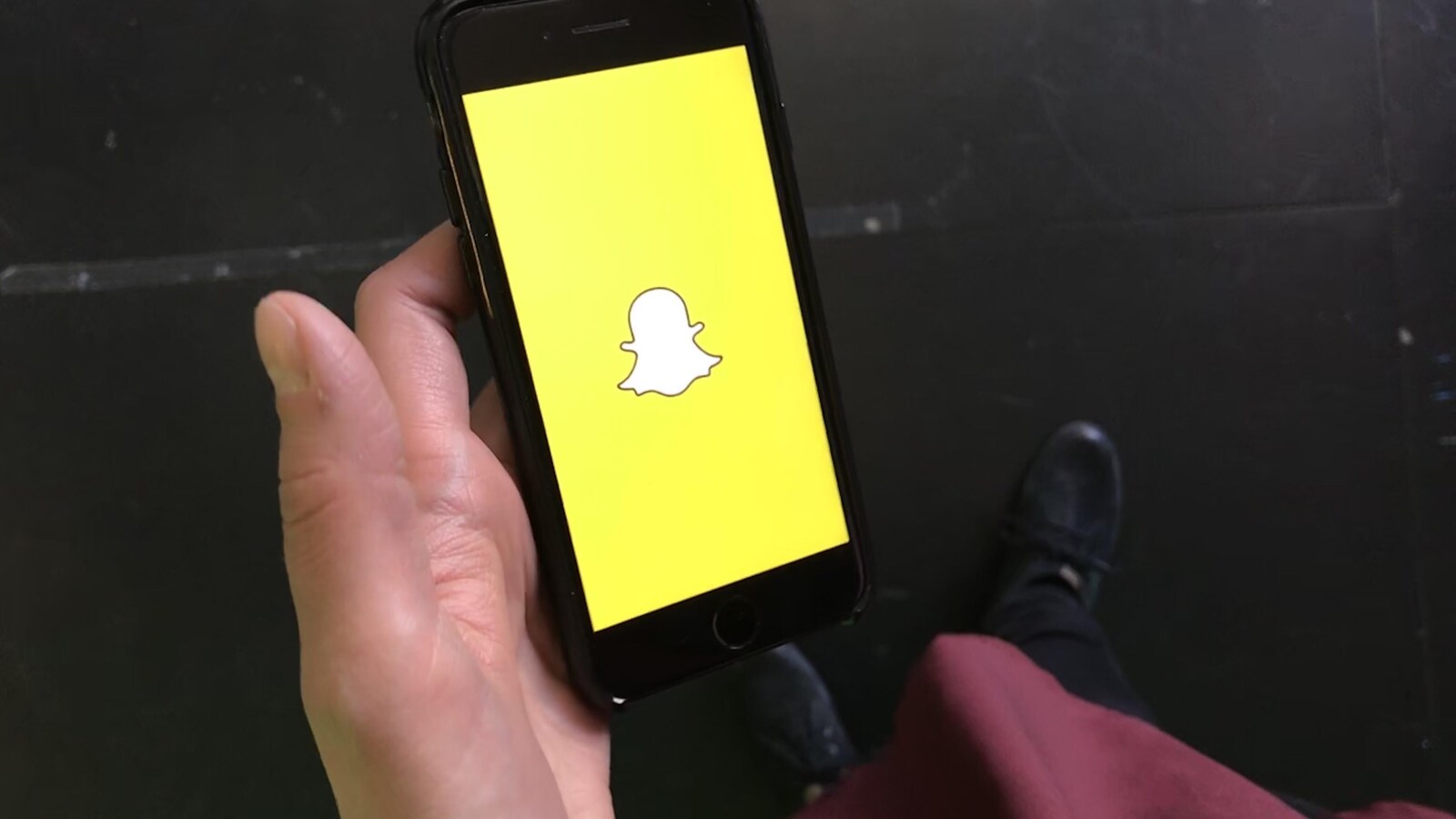 Un téléphone mobile dans une main avec le logo de Snapchat sur le téléphone.