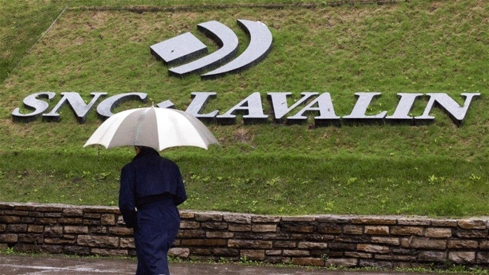 Un homme passe devant le logo de la compagnie SNC-Lavalin.