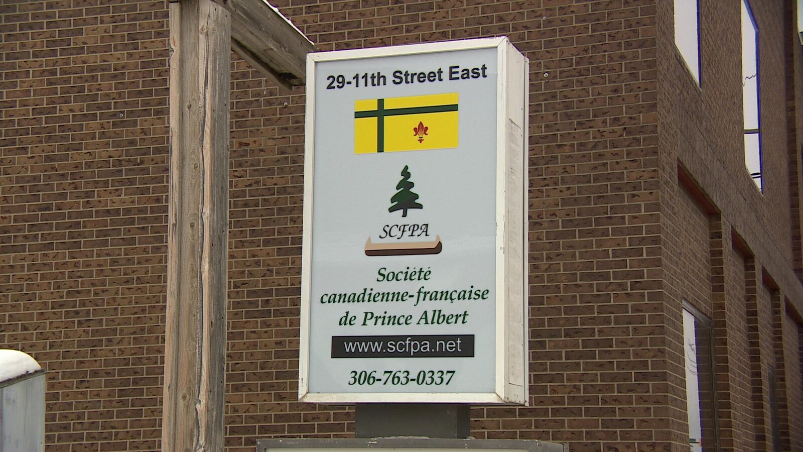 Affiche de la Société canadienne-française de Prince Albert devant l'édifice où se trouvent ses locaux.