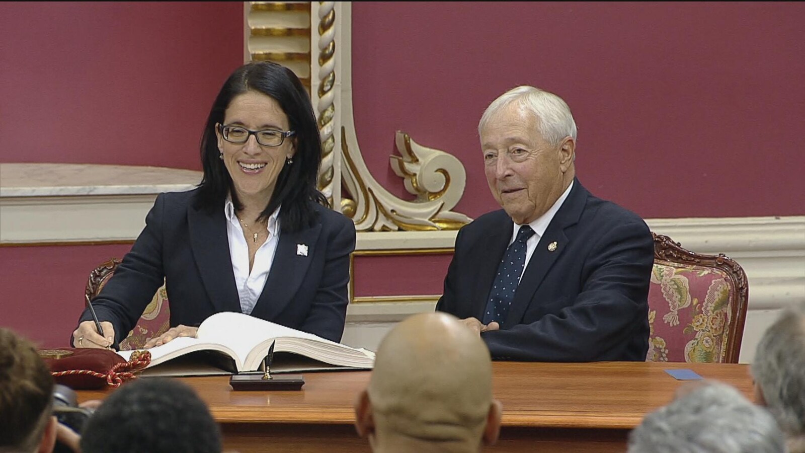Sonia Lebel qui signe aux côtés du Lieutenant-gouverneur.