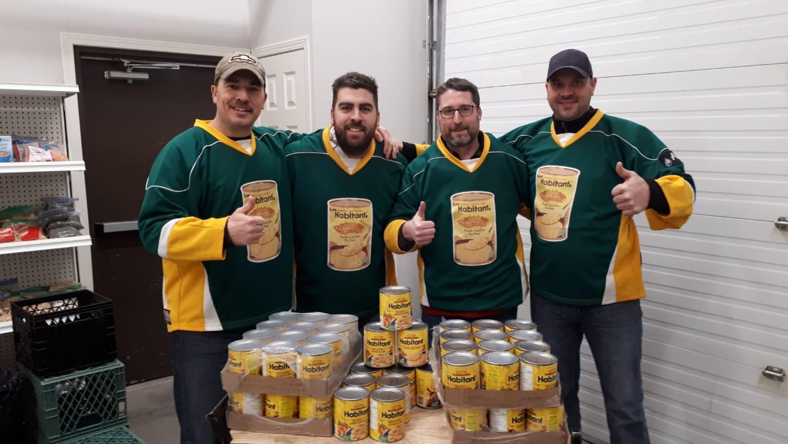 Quatre hommes le pouce levé donne des boîtes de soupe.