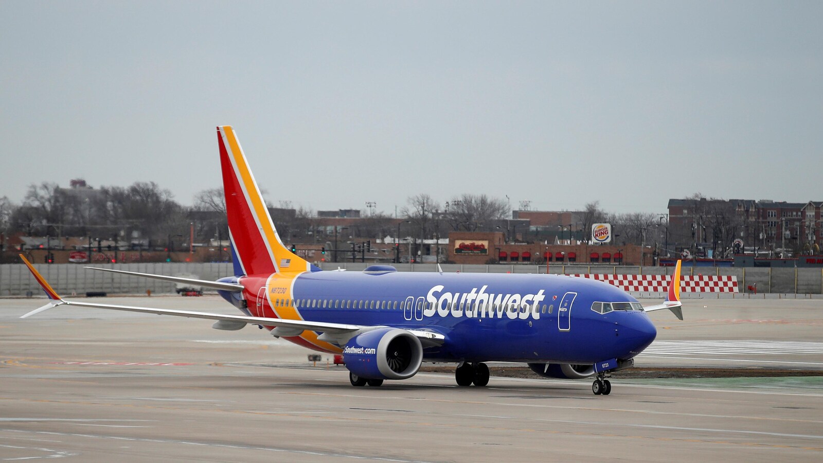 Un Boeing 737 MAX 8 de Southwest, aux couleurs bleu, rouge et jaune, est sur la piste d'atterrissage.