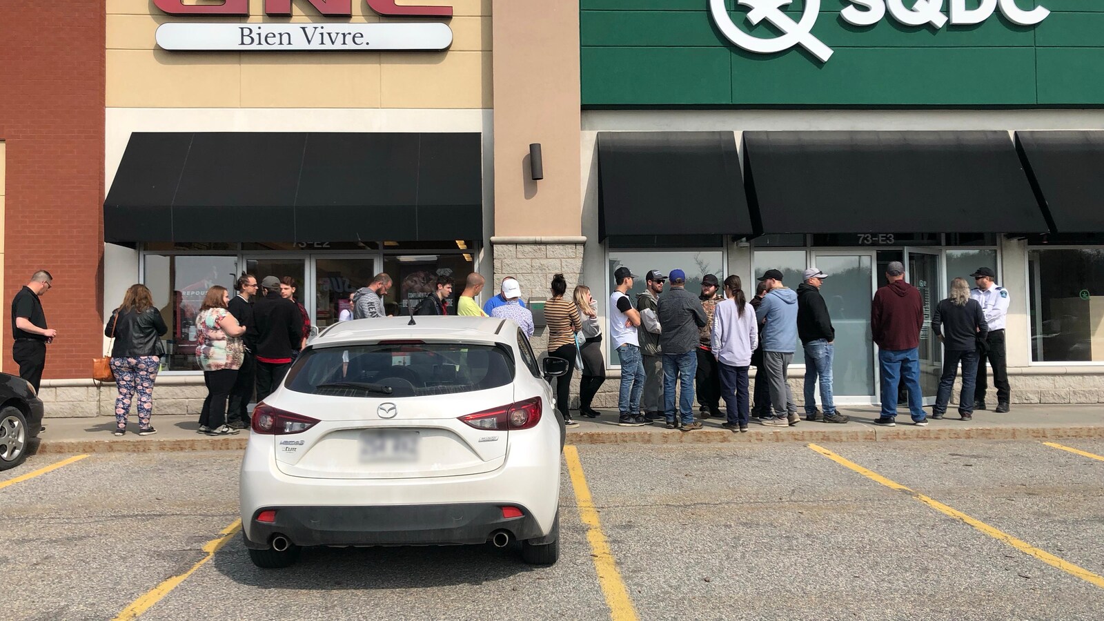 Une ligne de personnes devant un commerce de cannabis.