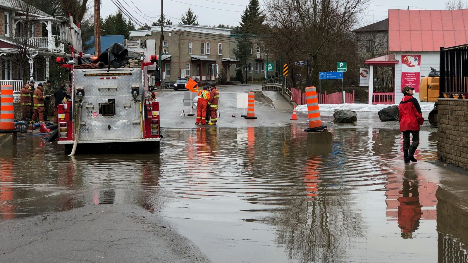 Un camion de pompiers est stationné dans l'eau, alors que des pompiers sécurisent les lieux.