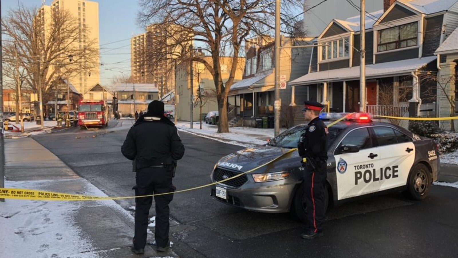 Photo de deux policiers qui se tiennent à côté d'une autopatrouille, bloquant une rue.