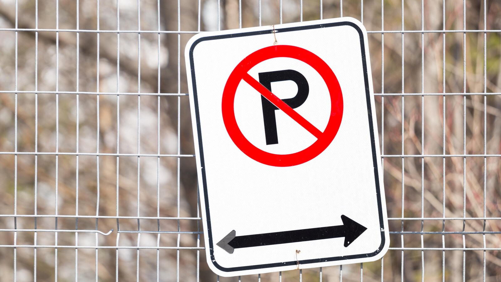 Affiche d'interdiction de stationner posée sur une clôture.