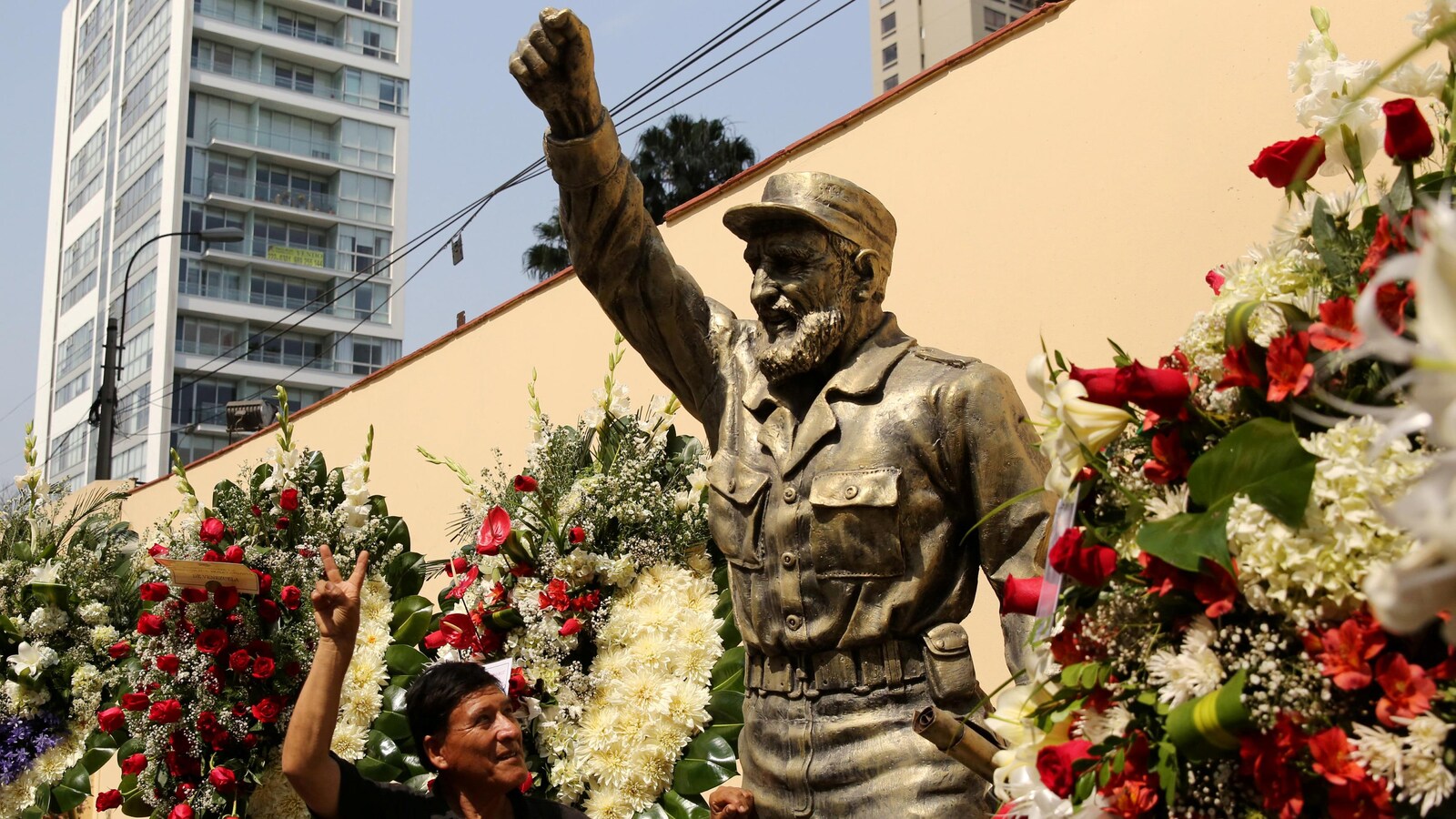 Un Cubain prend la pose devant une statue de l'ex-dirigeant Fidel Castro entourée de fleurs à Lima, au Pérou.