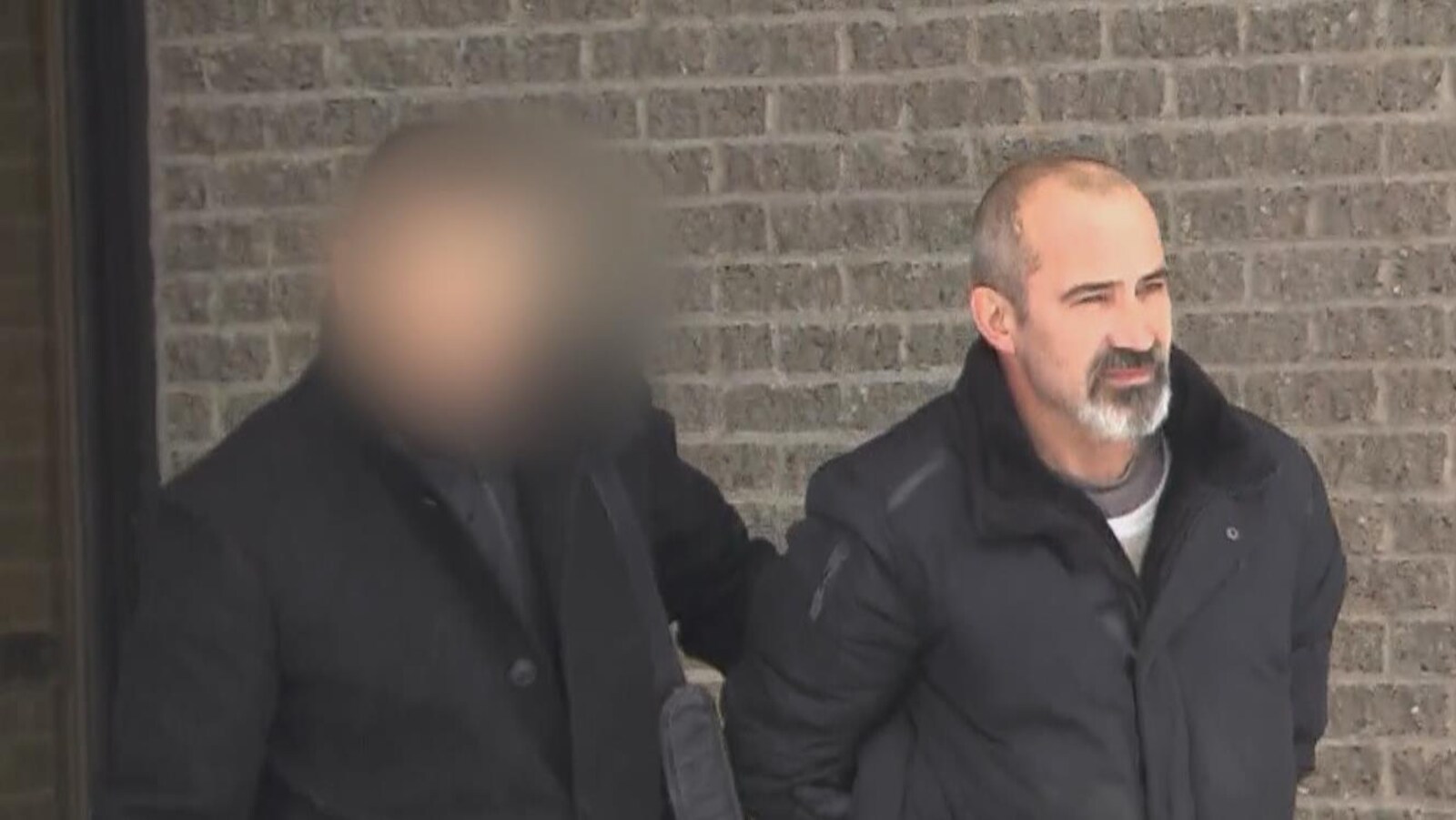 Un homme est escorté par un policier.