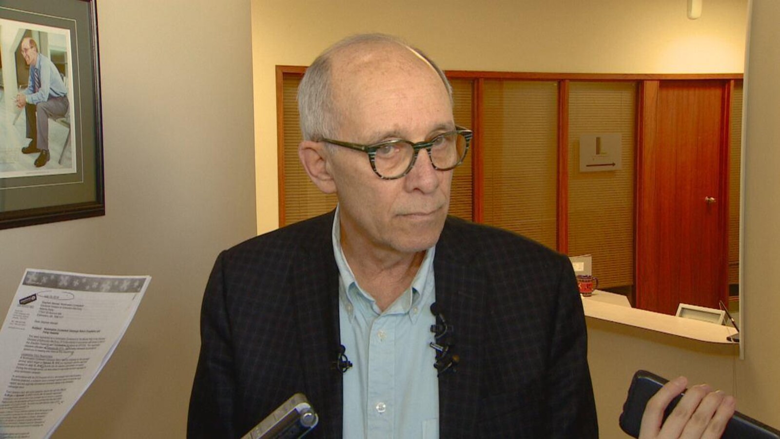 Le chef du Parti albertain, Stephen Mandel, porte des lunettes,une chemise et une veste devant des journalistes.