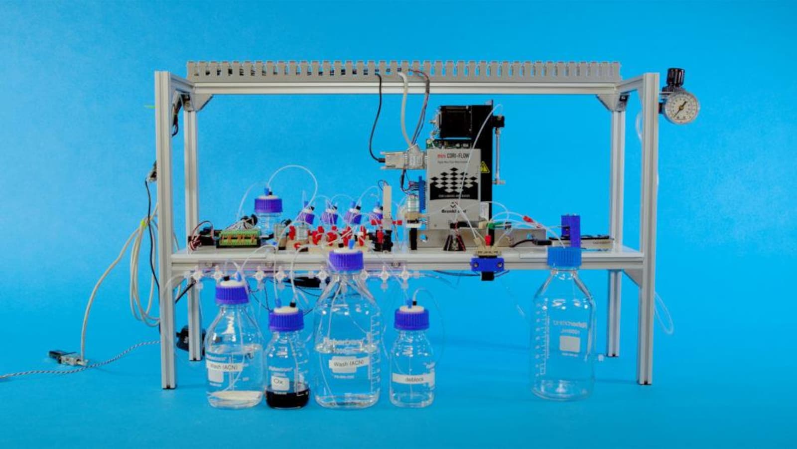 Une photo montrant un dispositif contenant des pièces électroniques branchées à un complexe système de bouteilles contenant des produits chimiques.