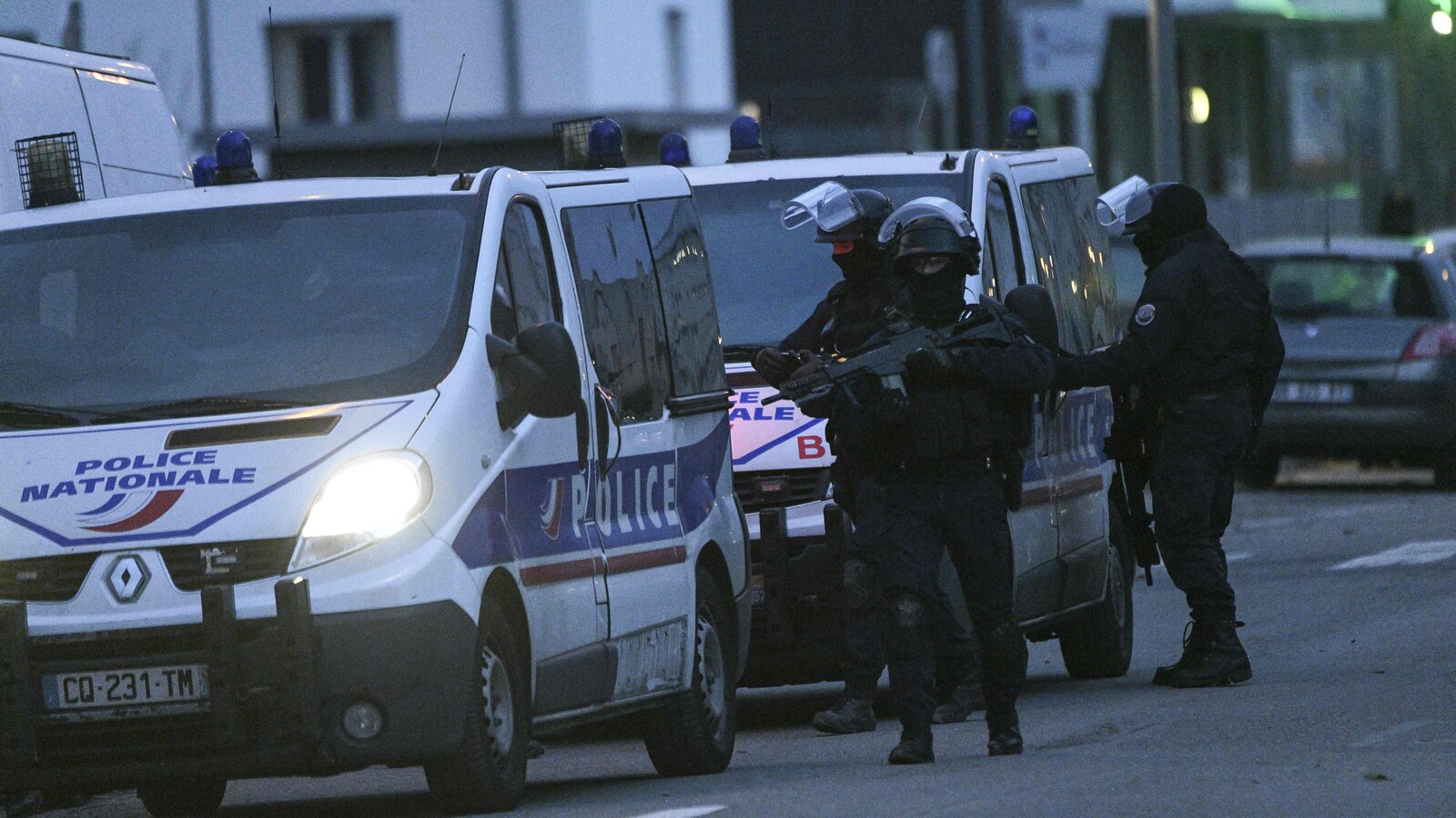 Des policiers lourdement armés sortent d'un véhicule. 