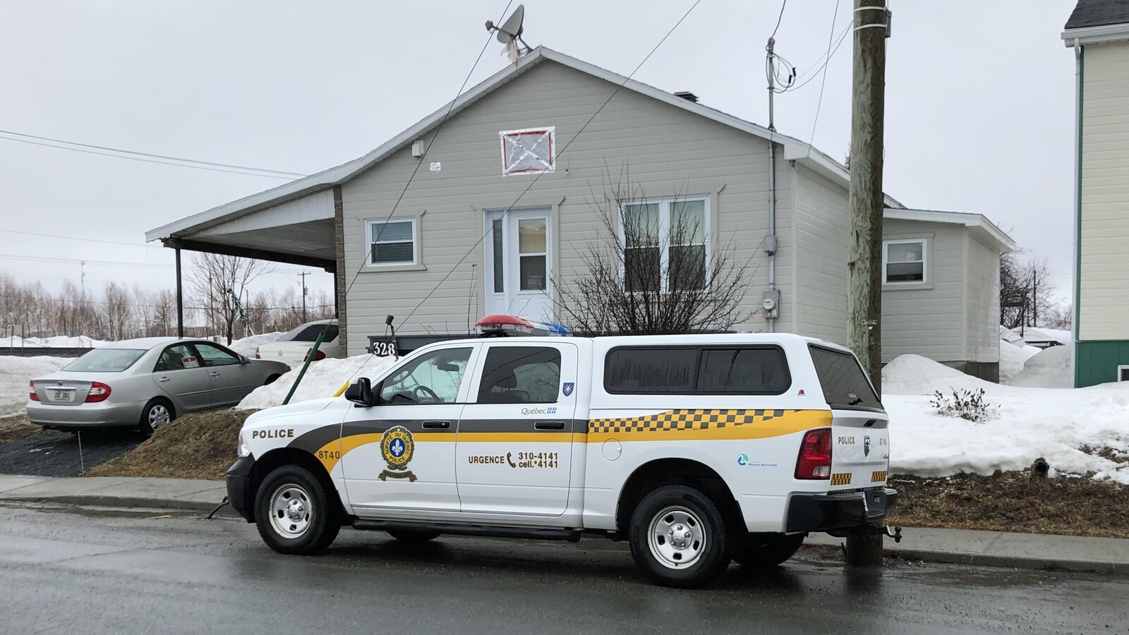 Une camionnette de la SQ est stationnée dans une rue résidentielle.
