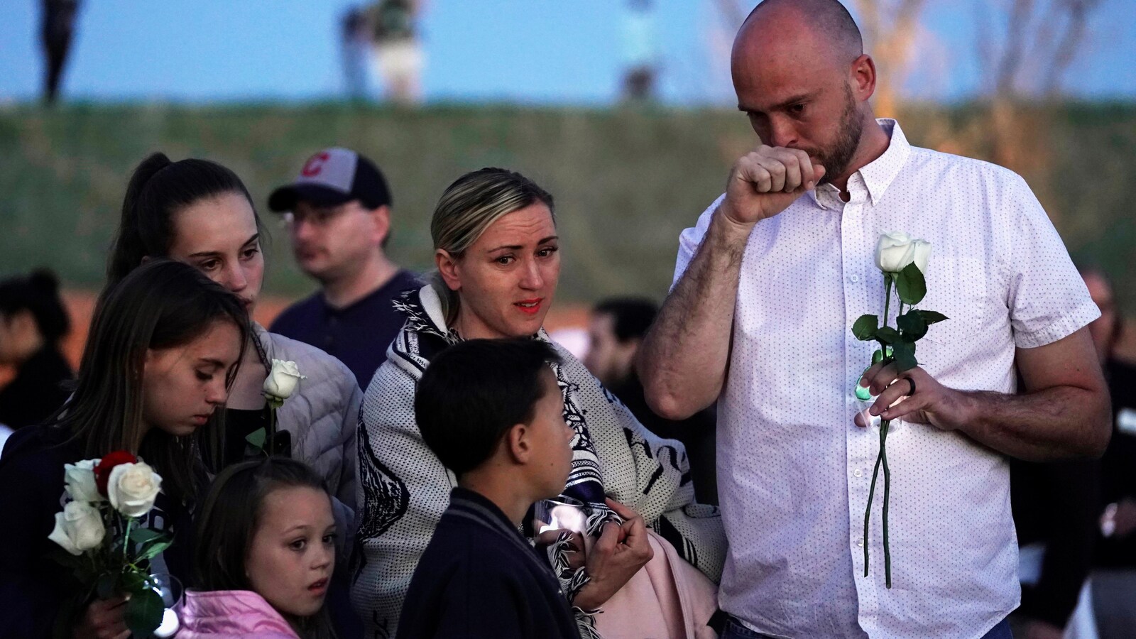 Un homme porte une rose blanche, il pleure, accompagné de ses enfants et de sa femme.