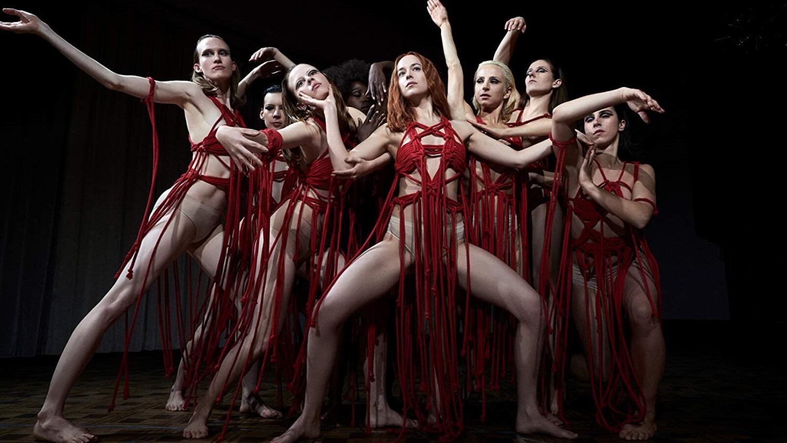 Des femmes vêtues de morceaux qui ressemblent à des cordes rouges sont regroupées pour une pose extraite d'un spectacle de danse.