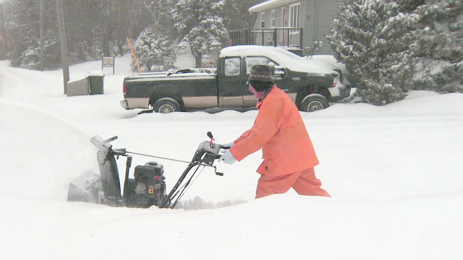 Un homme déneige avec une souffleuse.