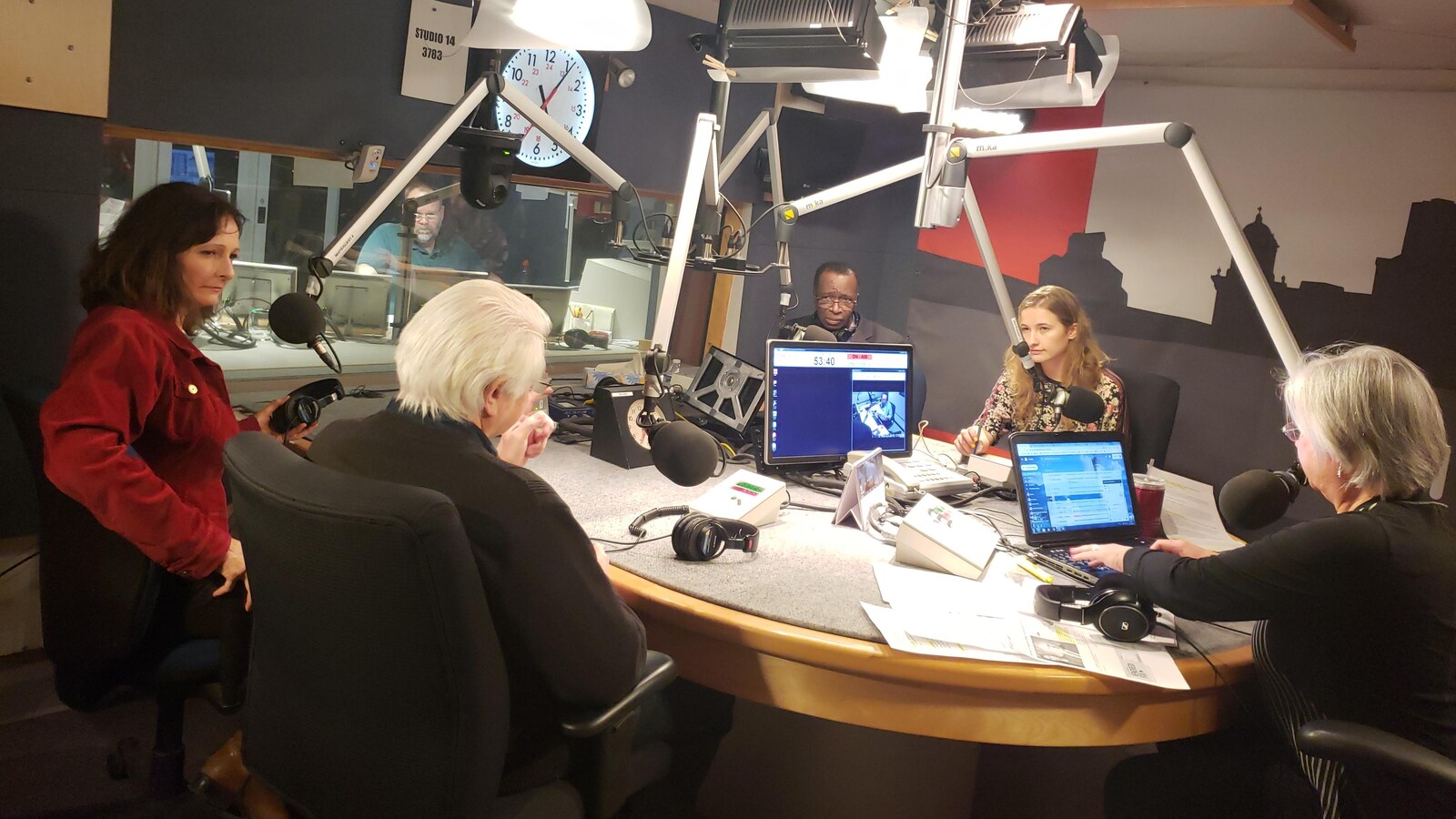Plusieurs personnes autour d'une table et de micros dans un studio de Radio-Canada.