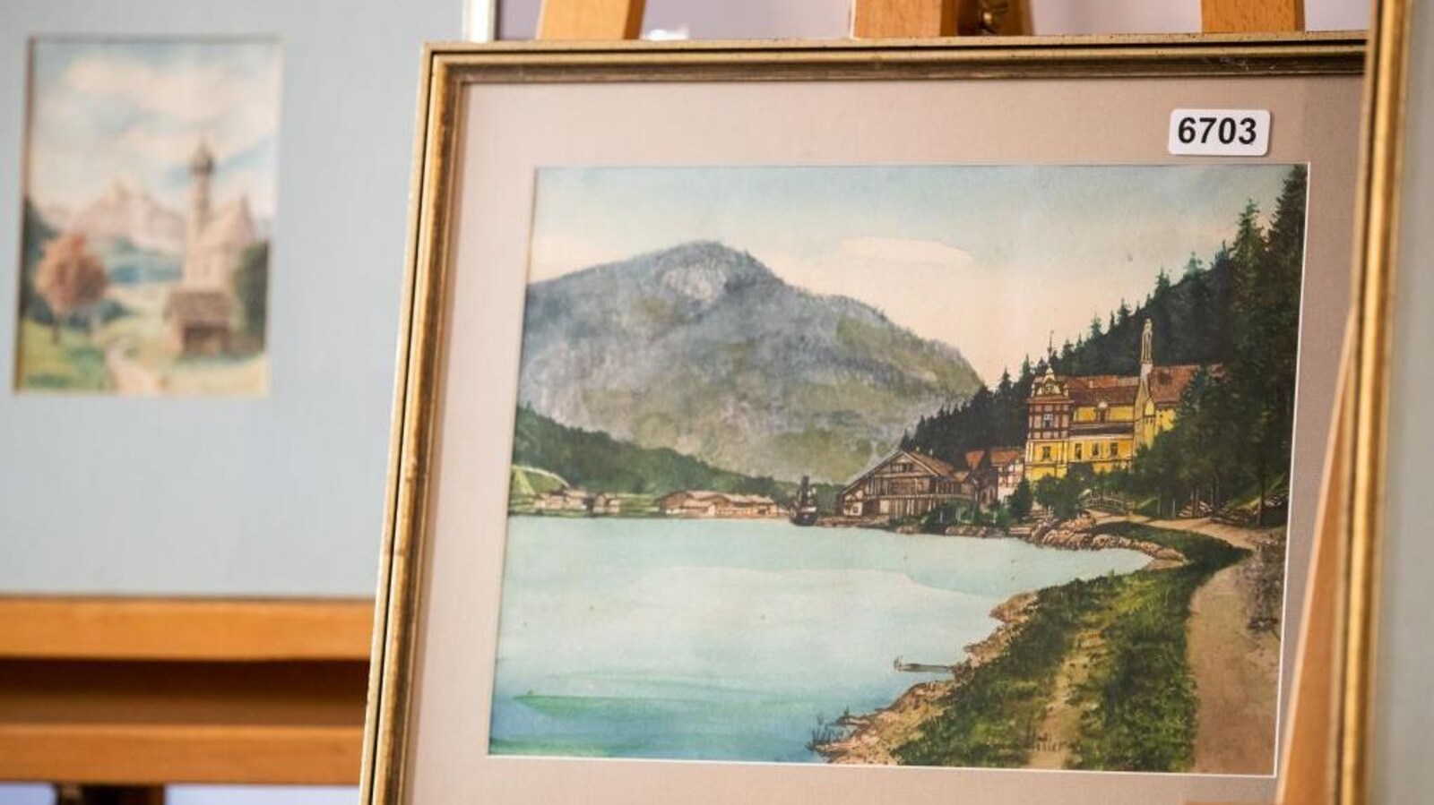 Tableau représentant un village allemand au bord de l'eau avec une montagne au fond.