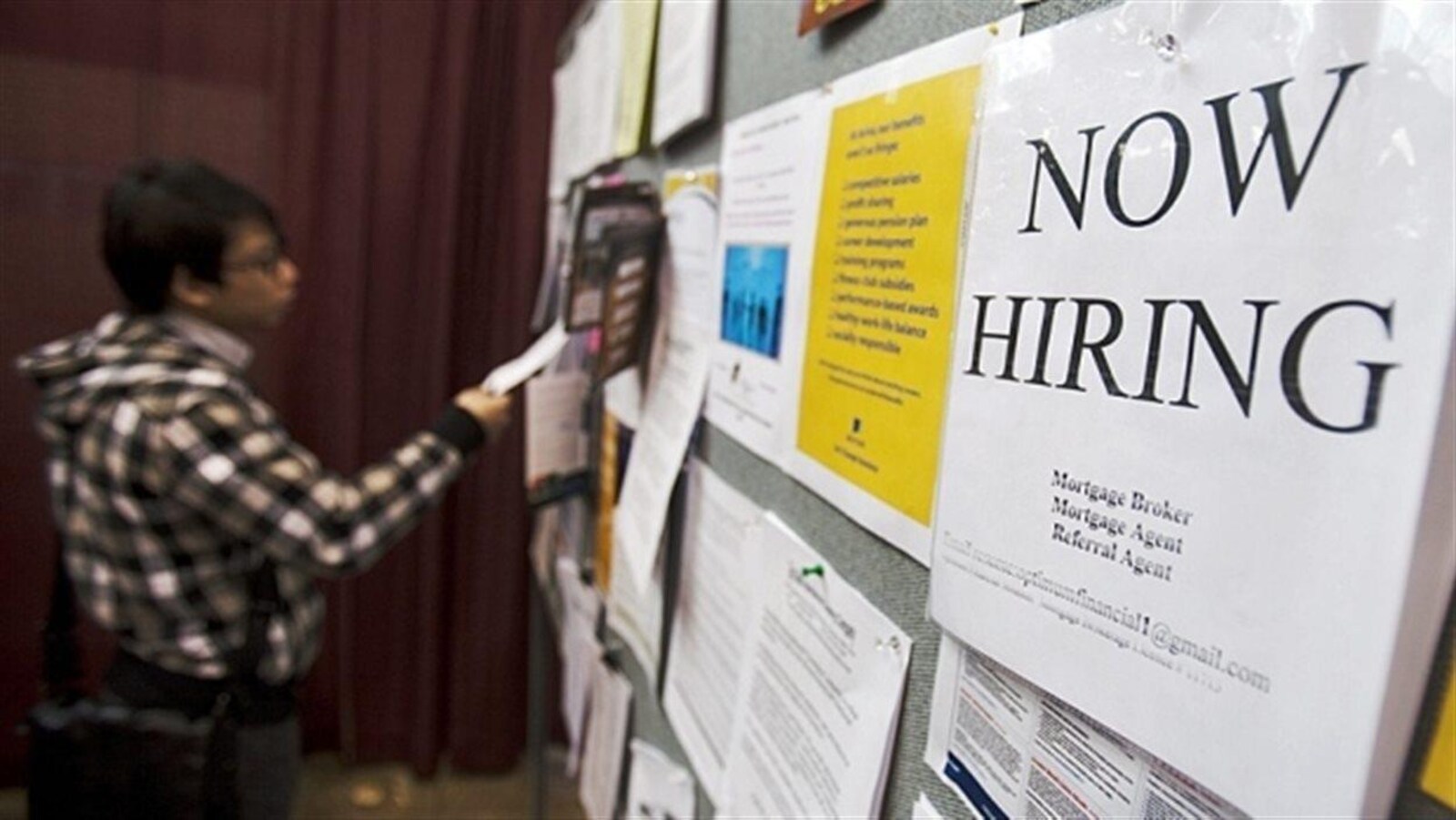 Une personne devant un tableau d'annonces d'emploi.
