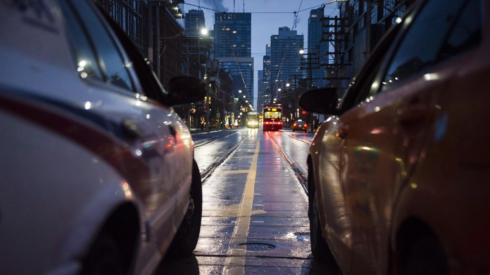 Une autopatrouille et un taxi dans une rue de Toronto où l'on aperçoit des tramways au loin.
