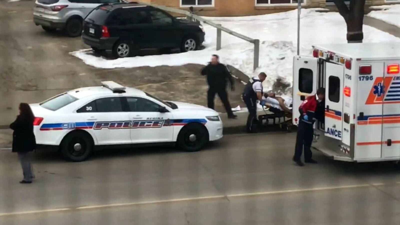 Le chauffeur de taxi blessé est allongé sur un brancard. Il s'apprête à être placé dans une ambulance avant son transport à l'hôpital.