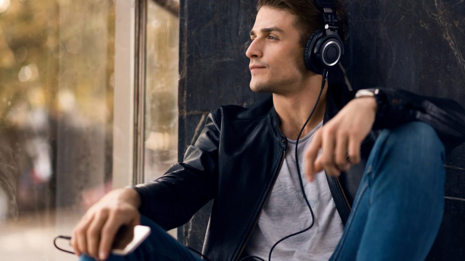 Un jeune homme écoute de la musique sur son téléphone grâce à son casque.