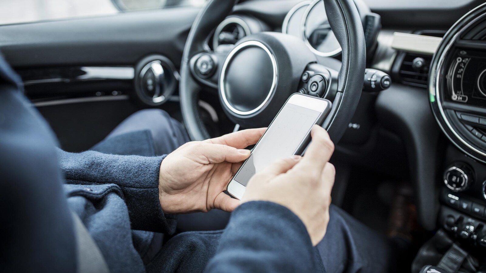 Un homme assis dans une voiture utilise son téléphone cellulaire.