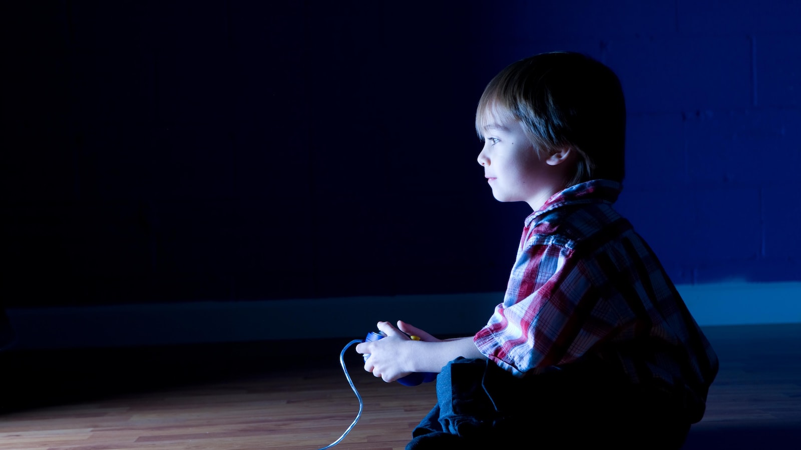Un enfant avec une manette devant un écran.